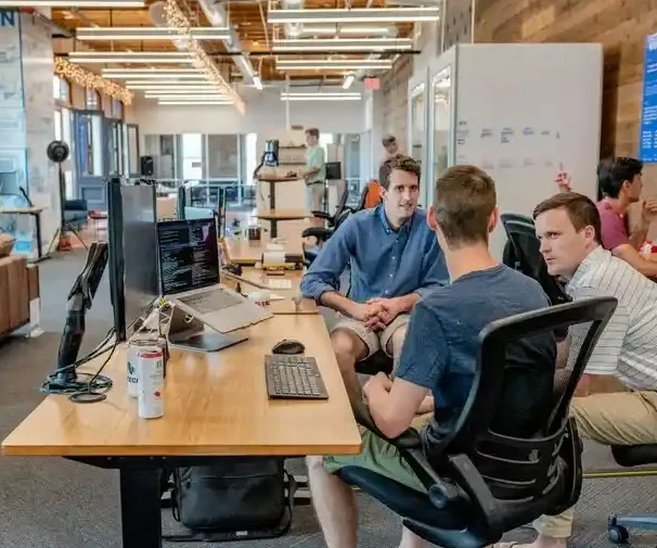 Die Vorteile der Unternehmensberatung Drei Männer arbeiten in einem modernen Büro, diskutieren an einem Tisch mit Laptops.